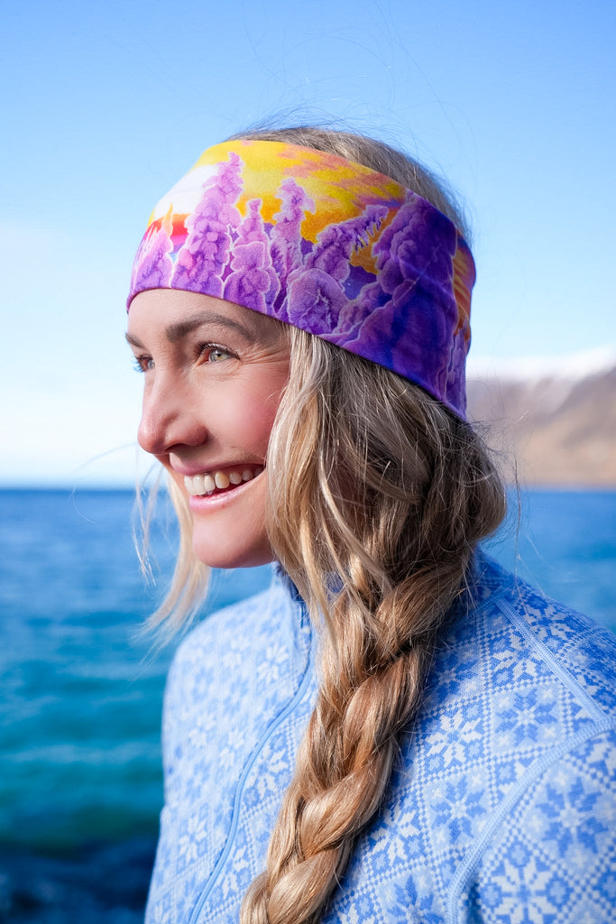 A side profile of a blond woman wearing The Snowy Path headband in front of a lake